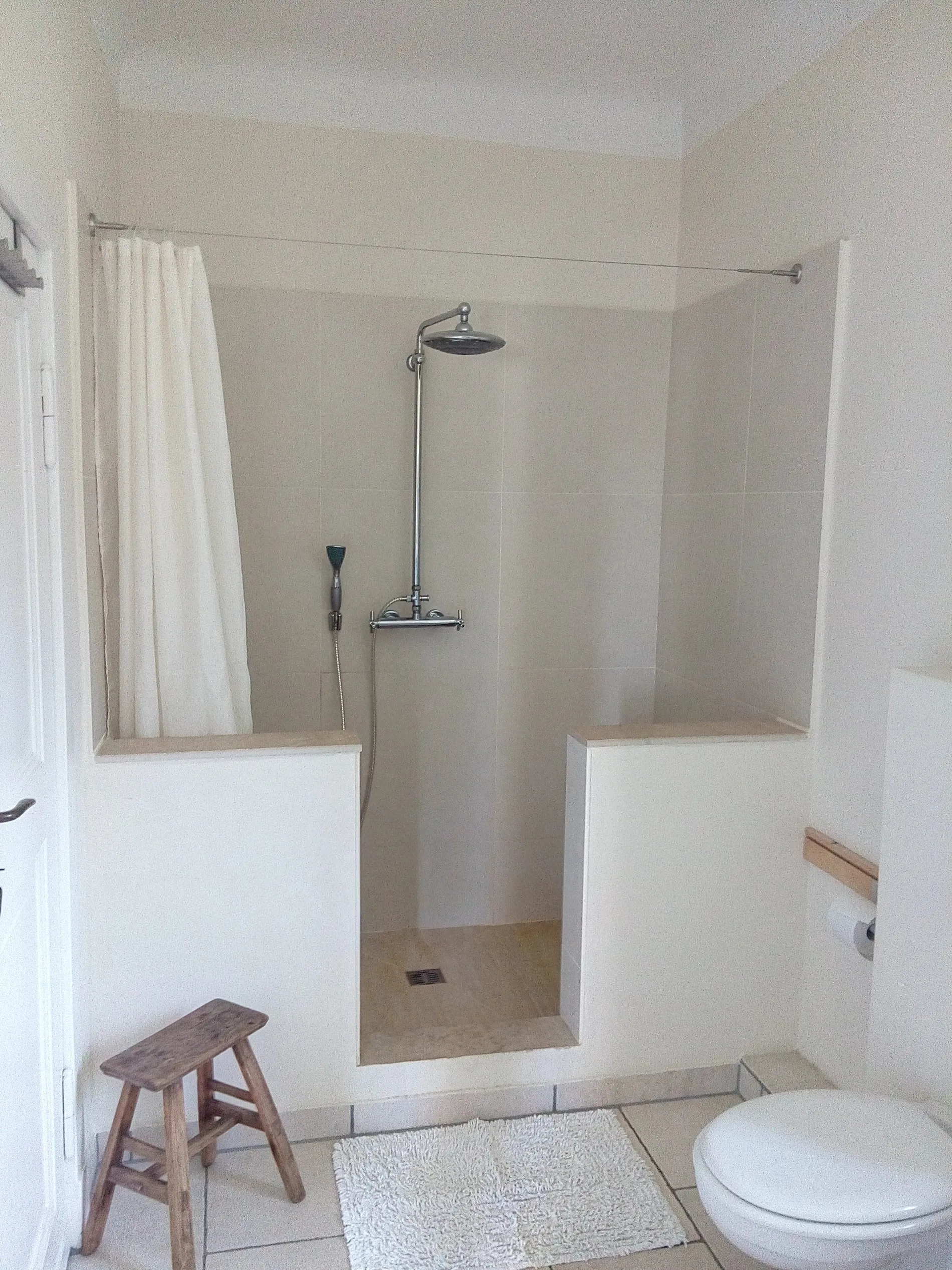 Dusche mit Regenbrause und Holzhocker