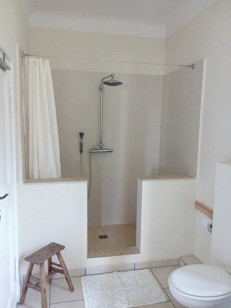 Dusche mit Regenbrause und Holzhocker