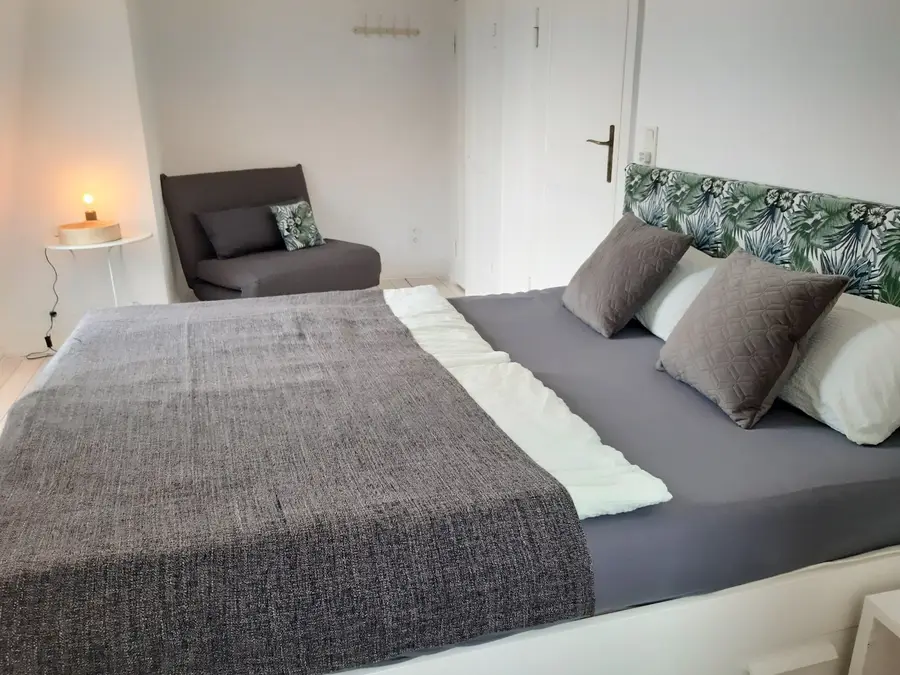 Schlafzimmer mit Doppelbett und grauer Tagesdecke