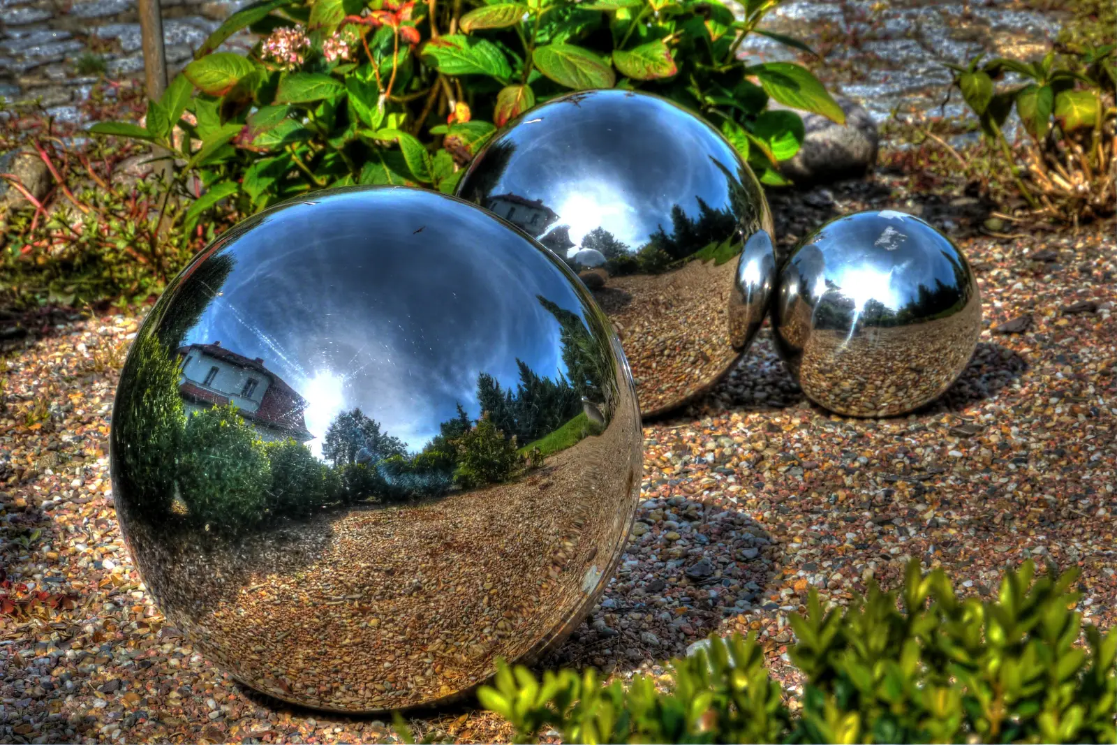 Drei spiegelnde Edelstahlkugeln im Kiesbeet