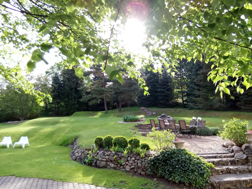 Sitzplatz im Garten unter alten Bäumen, Sonne durch das Laub
