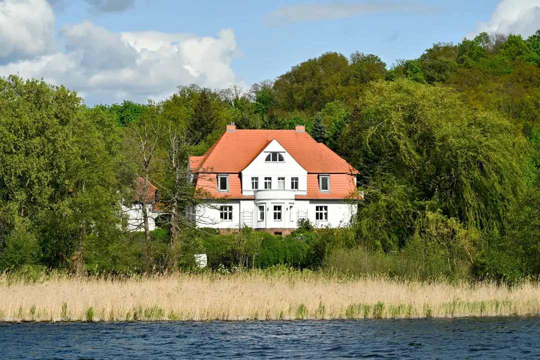 Der Gutshof Schwielowsee vom Wasser aus gesehen, mit Schilfgürtel im Vordergrund