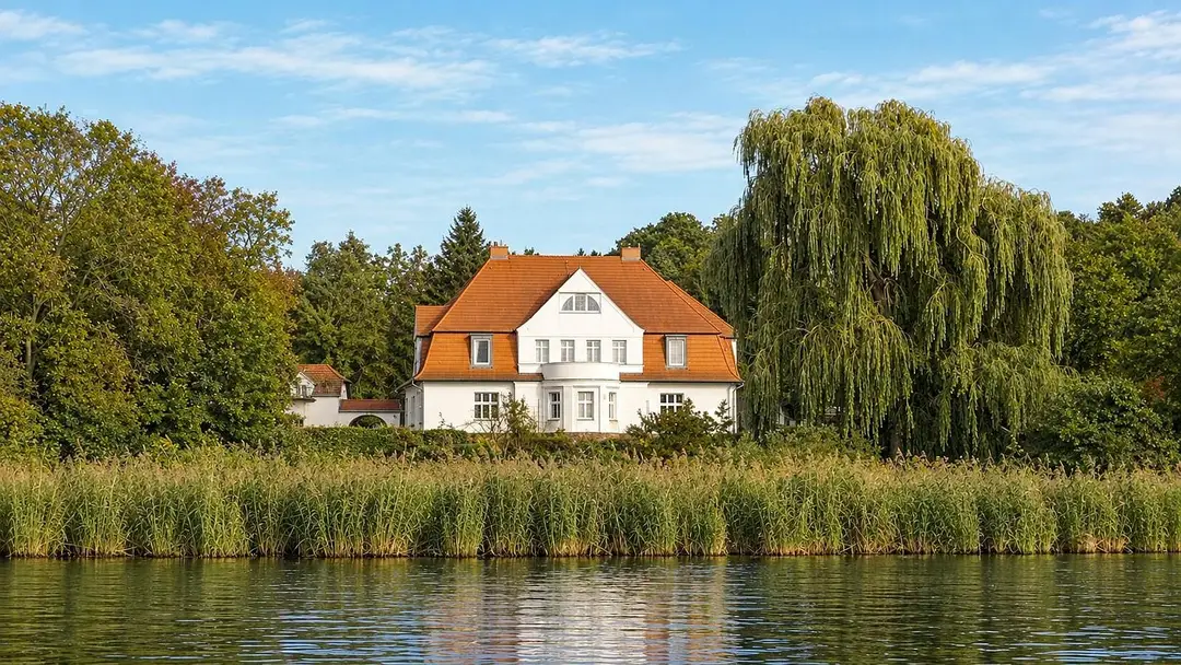 Der Gutshof Schwielowsee vom Wasser aus gesehen, mit Schilfgürtel im Vordergrund
